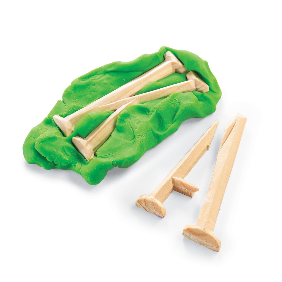 Green modeling material holds several wooden golf tees, while two tees rest beside it on a white surface.