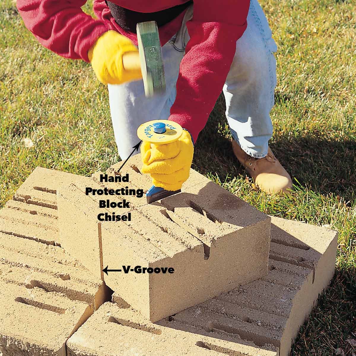 A person uses a hammer to strike a chisel on a stone block, while a grassy area serves as the work environment.