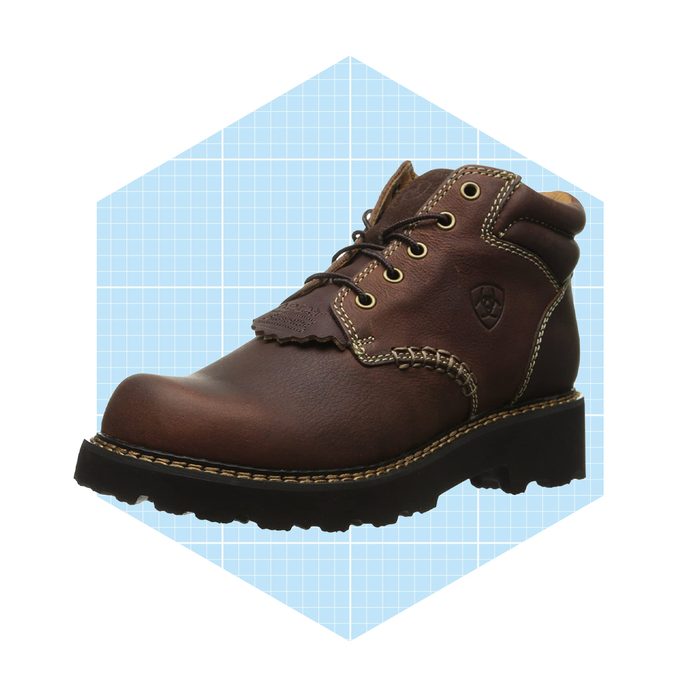 A brown leather boot with a rugged sole stands on a light blue grid background, showcasing its lace-up design and decorative stitching.
