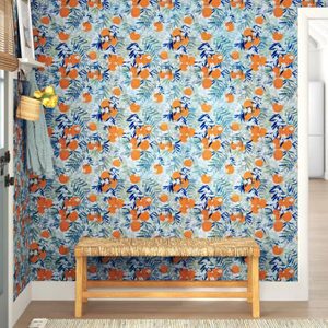 A wooden bench rests against a floral-patterned wall adorned with orange fruits and green leaves, set in a bright, modern interior space.