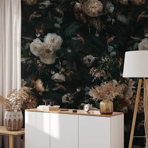 A stylish cabinet holds decorative items, beside a floor lamp, against a dark floral wallpaper featuring various plants and flowers in a serene indoor setting.