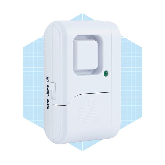A white security alarm device is mounted, featuring a button and a small green light, set against a light blue geometric background.