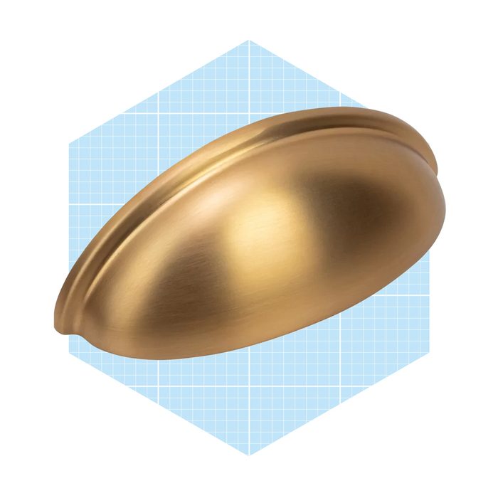A shiny, gold-colored cabinet knob rests against a light blue, grid-patterned background, suggesting a sleek, modern design for home decor.