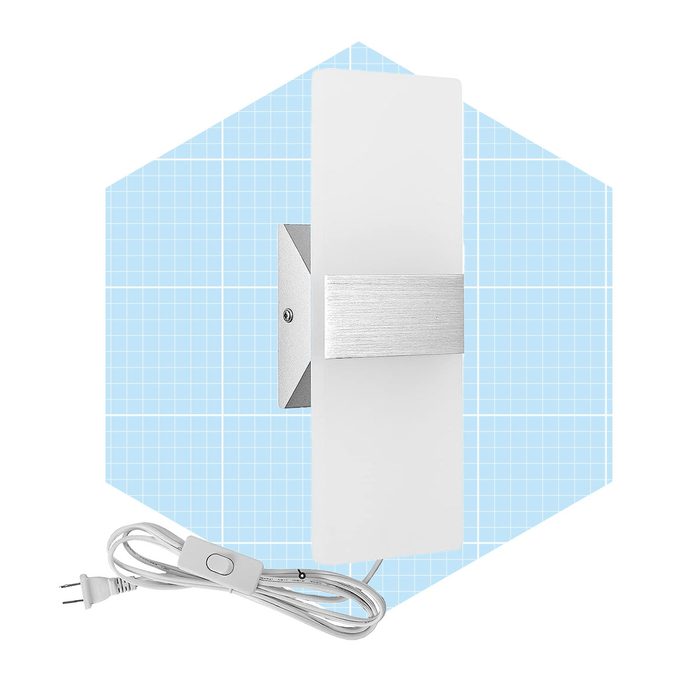 A rectangular wall lamp is mounted, illuminating a light surface. It’s connected to a power cord and switch, set against a blue grid background.