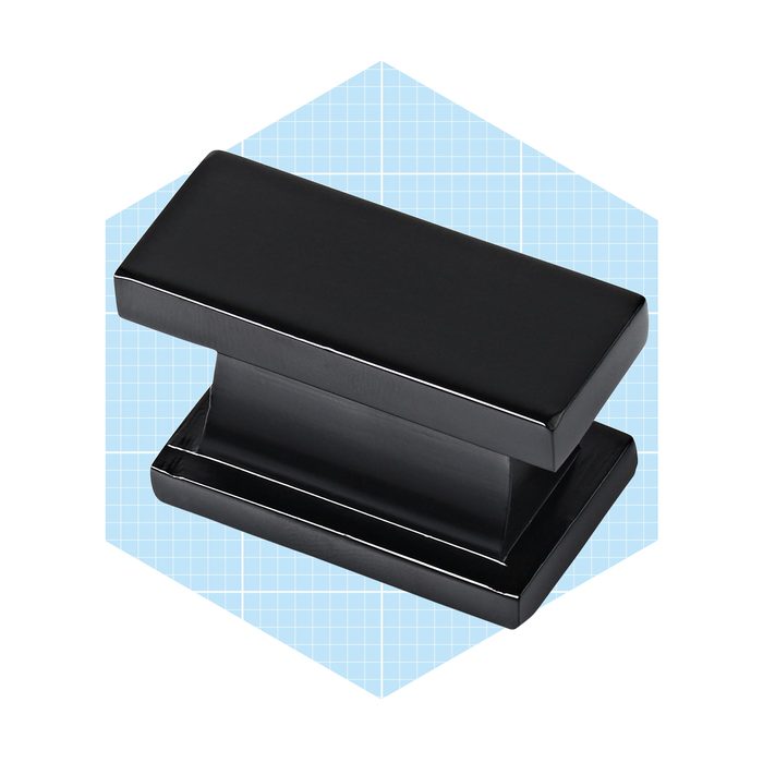 A glossy black paperclip sits upright, designed to hold sheets together, set against a light blue grid background.
