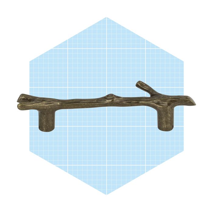 A decorative branch-shaped handle rests horizontally, designed for gripping. It is positioned against a light blue grid background, enhancing its natural appearance.