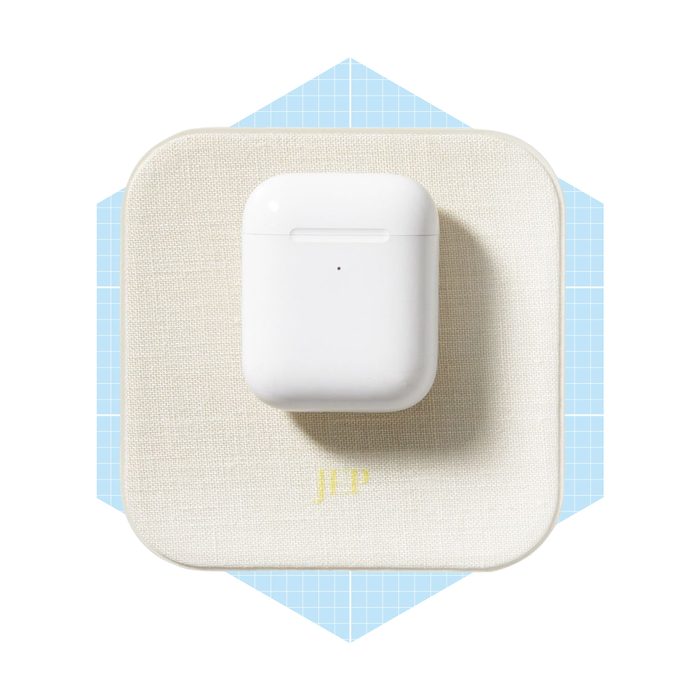 A white AirPods case rests on a textured cream surface, surrounded by a light blue geometric background, creating a modern and minimalistic aesthetic.