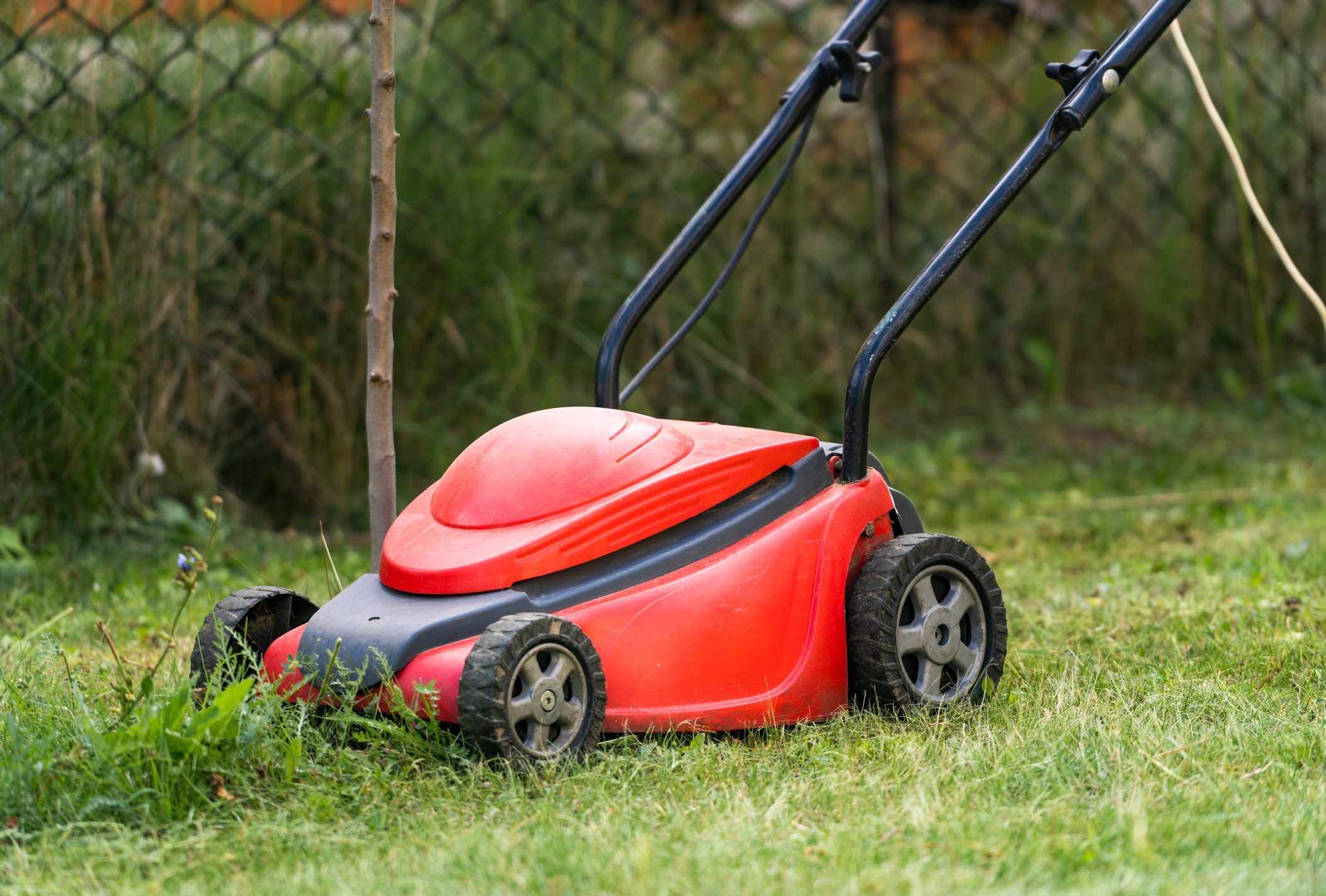 lawn mover at work on a green meadow at summertime